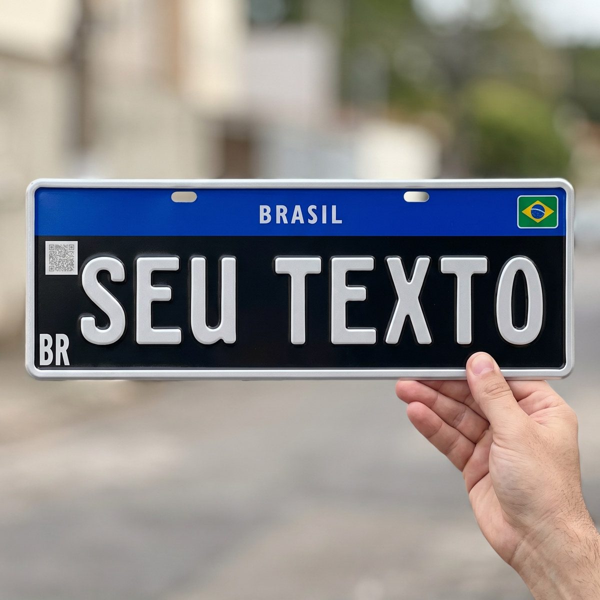 Placa colecionador preta segurada na mão, mostrando o tamanho real