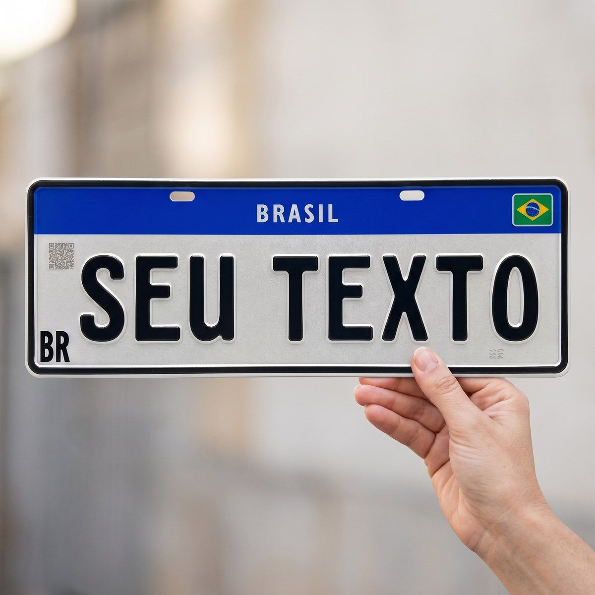 Placa Mercosul branca segurada na mão, mostrando o tamanho real