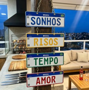 Quatro placas decorativas penduradas na área gourmet, escrito SONHOS, RISOS, TEMPO e AMOR