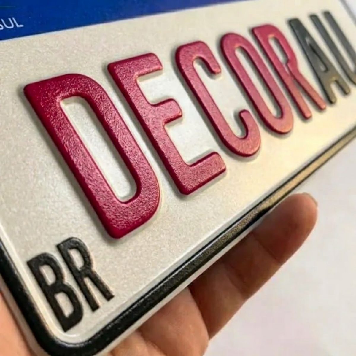 Detalhe aproximado das letras em alto relevo prensado, com a sombra na borda de cada letra