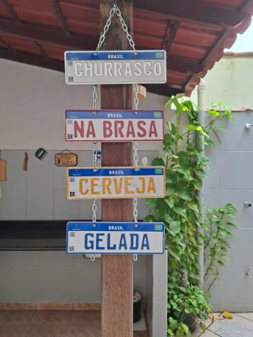 Quatro placas decorativas penduradas em corrente numa área de churrasco